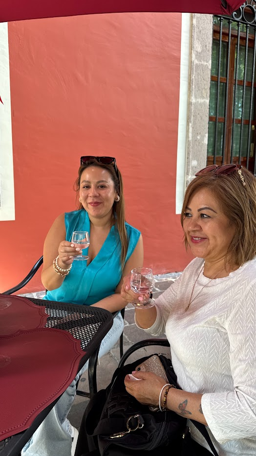 Dos invitadas brindando con copas de mezcal Casa España en la terraza