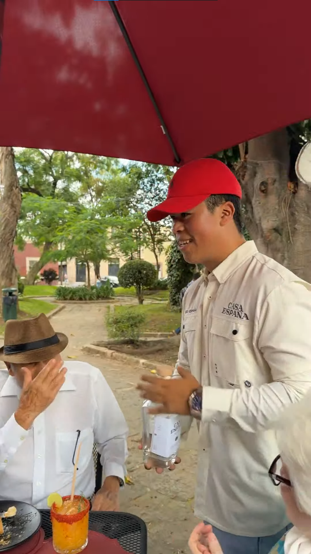 Anfitrión de Casa España sirviendo mezcal en una mesa del patio de Mestizaje