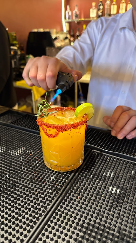 Coctel con mezcal Casa España flameado por el bartender en la barra